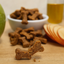 Gâteau végétal pour chat et chien à la caroube et pomme, texture croquante visible en gros plan, ingrédients naturels en arrière-plan.